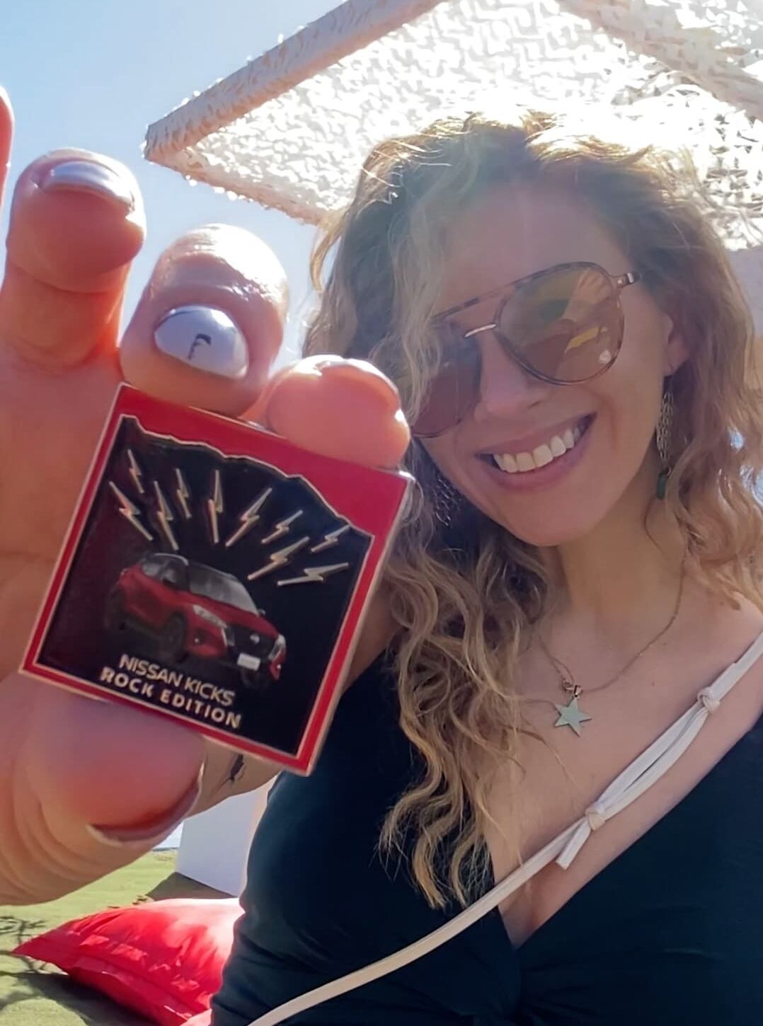 Mujer en Lollapalooza 2025 sosteniendo uno de los Pines Metálicos personalizados de Nissan Kicks Rock Edition fabricados por Rey del Pin.