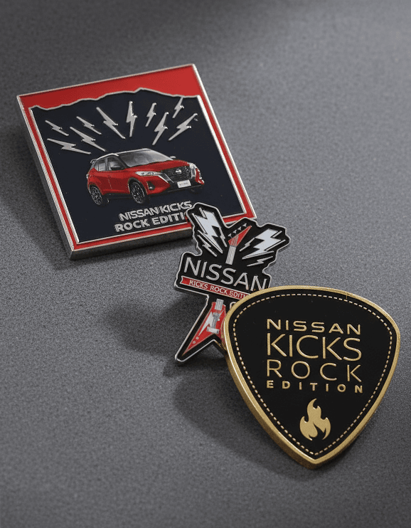 Tres pines metálicos corporativos personalizados fabricados para Nissan Kicks Rock Edition. Diseños esmaltados de auto SUV, guitarra eléctrica y uñeta sobre fondo gris.